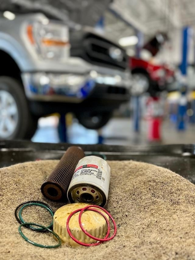 Close-up of automotive parts including oil filters, O-rings, and a fuel filter laid out on a shop cloth